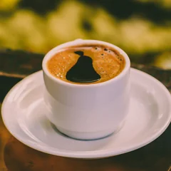 A steaming cup of black coffee with latte-art crema